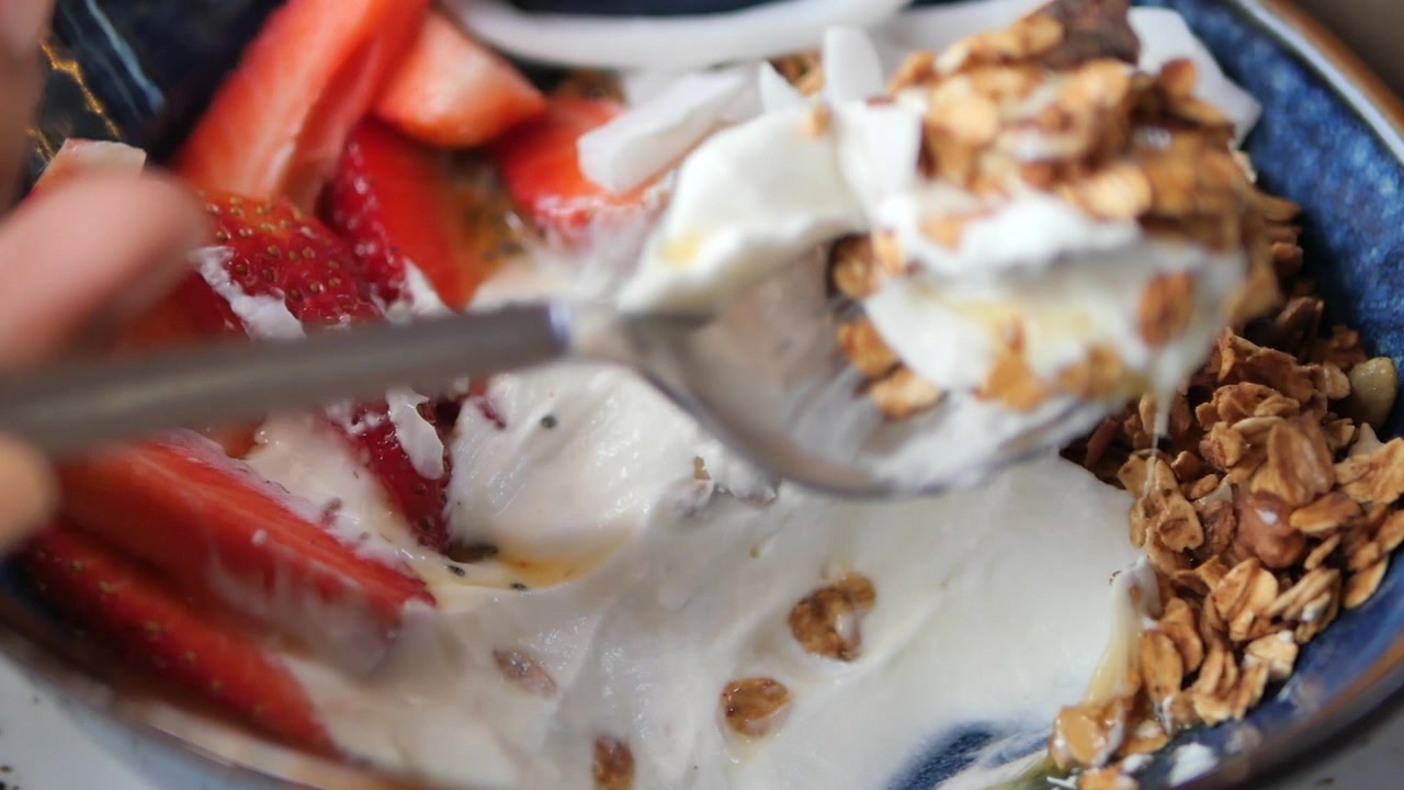 Puisant dans un bol de yaourt sain avec du granola, des fraises et de la noix de coco