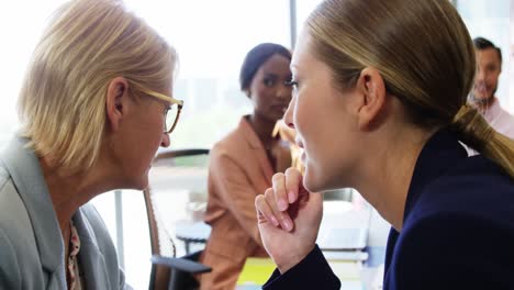 Two-businesswomen-whispering