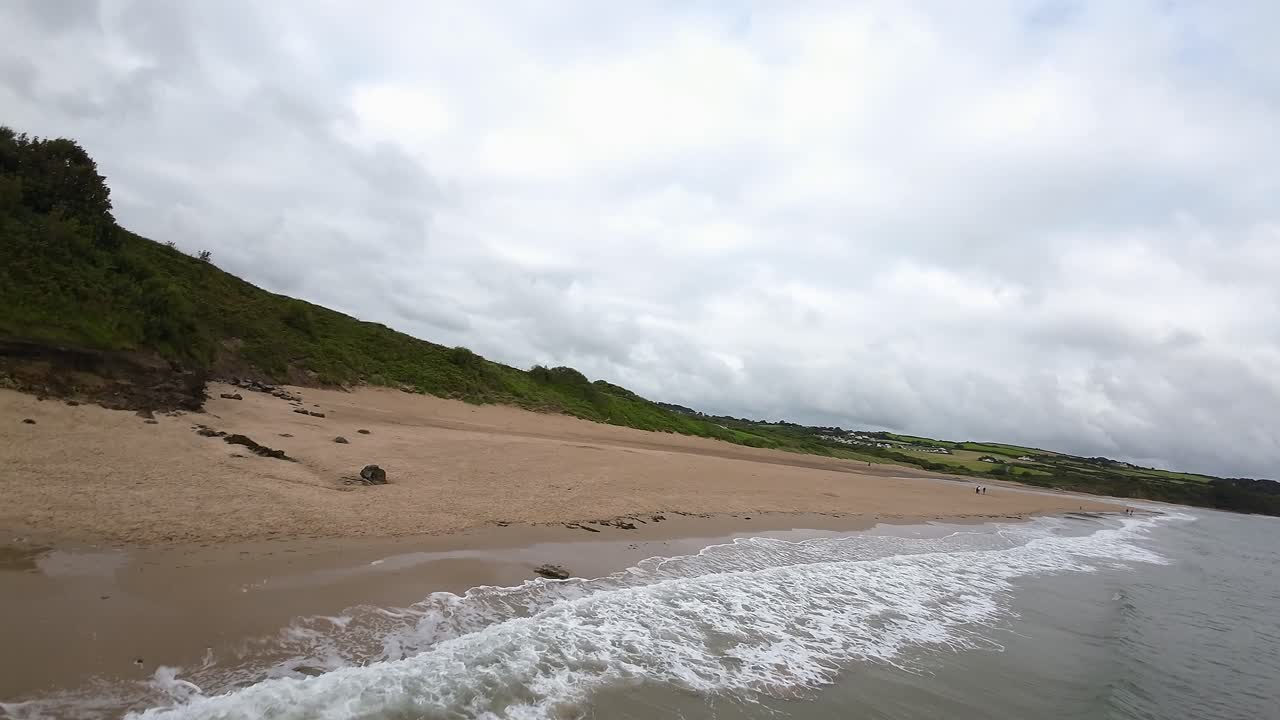 drone fpv acelerando a través de la playa rocosa a lo largo del camino costero angular sobre el paisajístico pastoreo rural de cría de ovejas