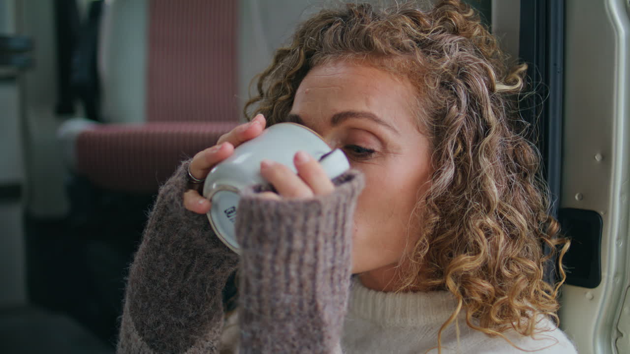 Primo piano di un turista in campeggio che beve caffè, godendosi la mattina di vacanza in solitudine.