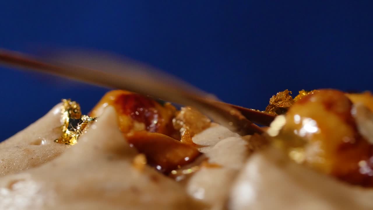 초콜릿, 카라멜, 견과류, 금 잎 이 들어 있는 디저트 의 클로즈업