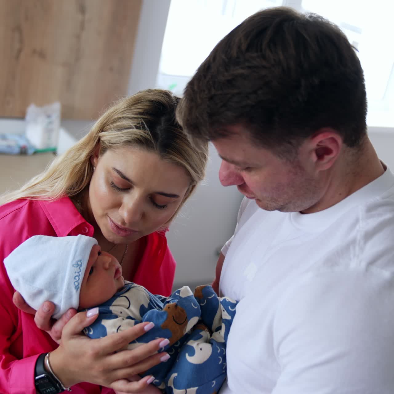 Genitori affettuosi che si prendono cura del loro neonato subito dopo la nascita. Genitori felici che adorano il loro bambino. Interni del reparto ospedaliero sullo sfondo