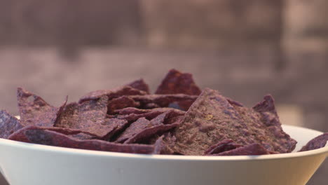 hand grabbing a chip from a bowl of blue nachos