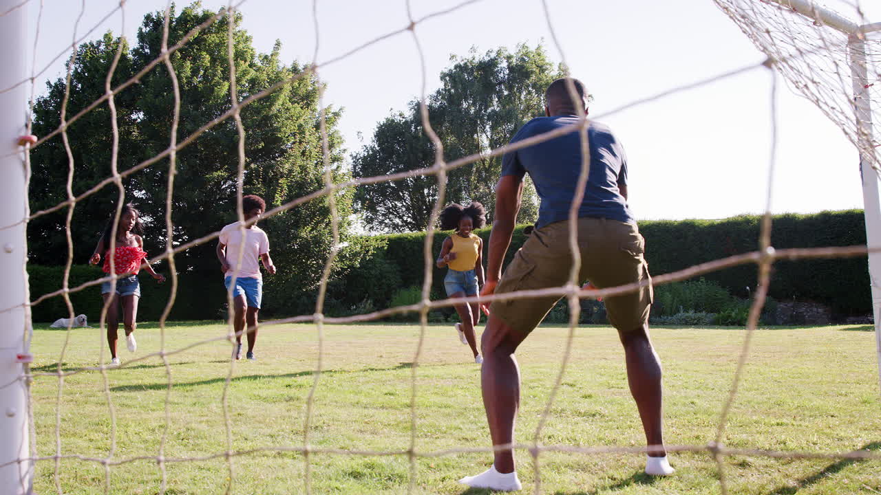 Duas casais adultos negros jogando futebol no jardim