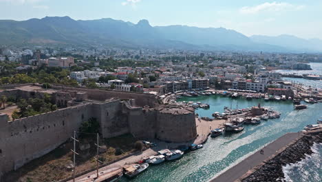 kyrenia harbor and castle on a sunny day with boats docked along the shore , aerial view