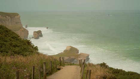 walking down a steep slope at the side of a hill leading down to the beach