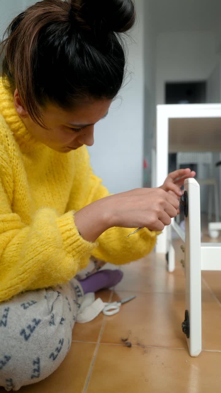Donna che assembla un mobile bianco sul pavimento di casa.