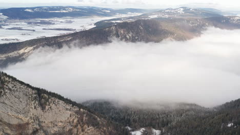 aerial of low hanging clouds in snow covered mountain pass