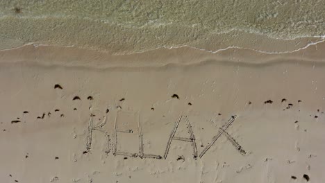 aerial camera looking straight down on relax inscribed in the sand on a beach