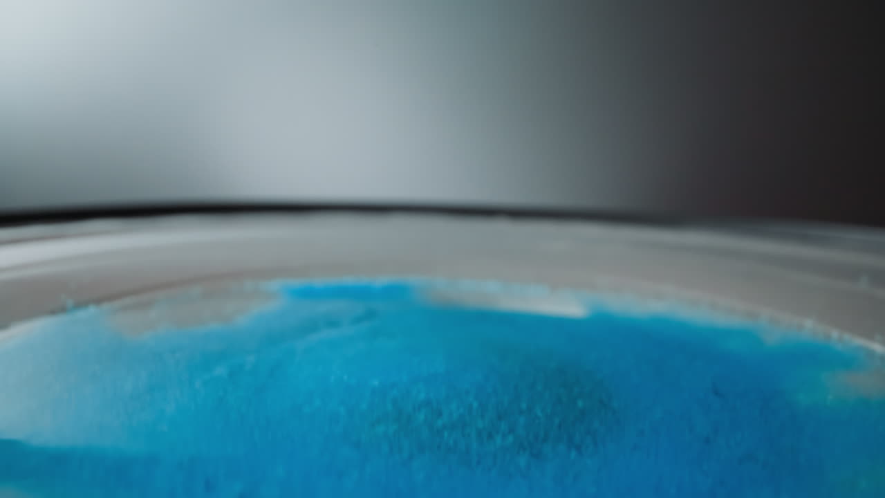 밝은 파란색 모래 결정의 층은 스피커에 놓여 있습니다