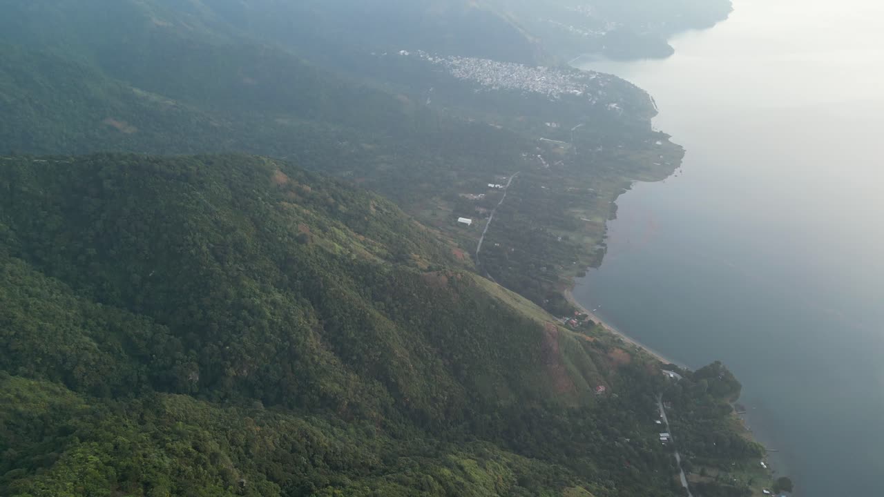 vista de avión no tripulado en guatemala panorámica de una montaña verde con un bosque lleno de árboles y un lago en un día nublado en aitlan