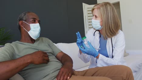 caucasian senior female doctor talking with male patient in bed both wearing face masks