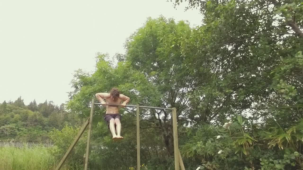 한 청년이 자연 속에서 벗은 몸으로 근력 운동을 한다