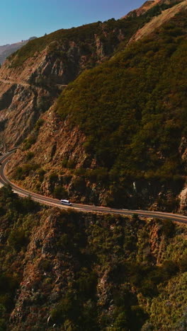 big sur morro bay rocks towering over the ocean waters. highway in the mountains by the pacific ocean on sunny bright daytime. vertical video