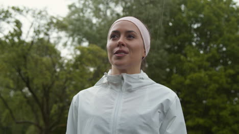 close up de mulher usando faixa na cabeça exercitando mantendo-se em forma correndo na chuva 3