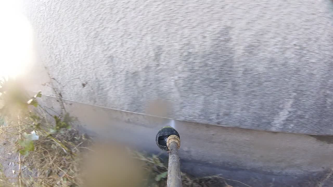 Idropulizia dell'angolo del muro del cortile, manutenzione con idropulitrice, POV.