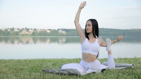 A Beautiful Brunette Does Yoga on the Background of a Lake Morning Workout Outdoors a Beautiful Brunette Does Yoga on the Background of a Lake Morning Workout Outdoors