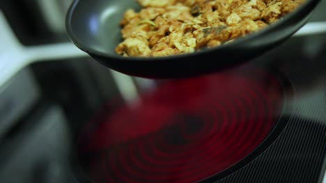 slow motion shot of someone cooking sizzling chicken in a pan over a stove