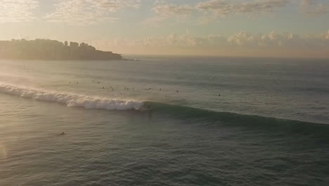 goofy foot surfer dando un paseo largo y agradable con un barril al final poco después del amanecer en bondi beach, sydney, australia
