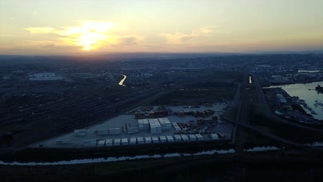 footage of sunset overlooking yachts moored with traffic on a road and shipping containers to be transported to ships by trucks