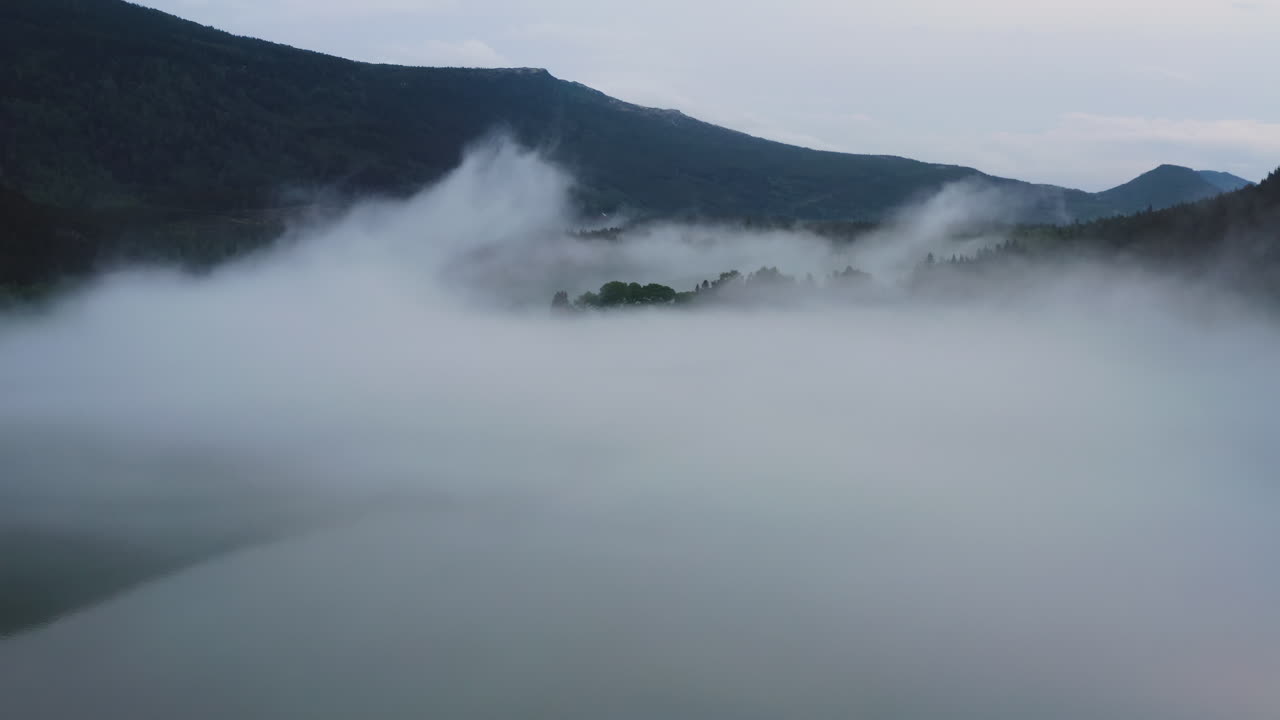 Flight over a foggy river. The mist is hanging low over the landscape creating a dark mystical mood over the whole scene
