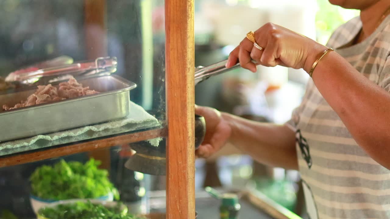 vendedor prepara fideos de cerdo en el mercado de bangkok