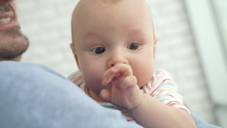 Baby-face-looking-in-camera.-Portrait-of-adorable-kid-in-father-hands