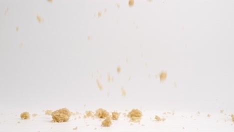 brown sugar pieces falling onto white studio backdrop in 4k slow motion