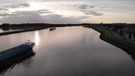 Barco-Navegando-Con-Una-Plataforma-De-Almacenamiento-Vacía-Contra-El-Cielo-Del-Atardecer-En-Las-Vías-Fluviales-Del-Sur-De-Holanda-En-Holanda