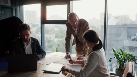 Young-Boss-in-a-modern-office,-a-blond-man-in-glasses-with-a-light-brown-beard-tells-his-colleagues-what-they-need-to-do-and-thinks-about-upcoming-issues.-Modern-office-with-panoramic-windows