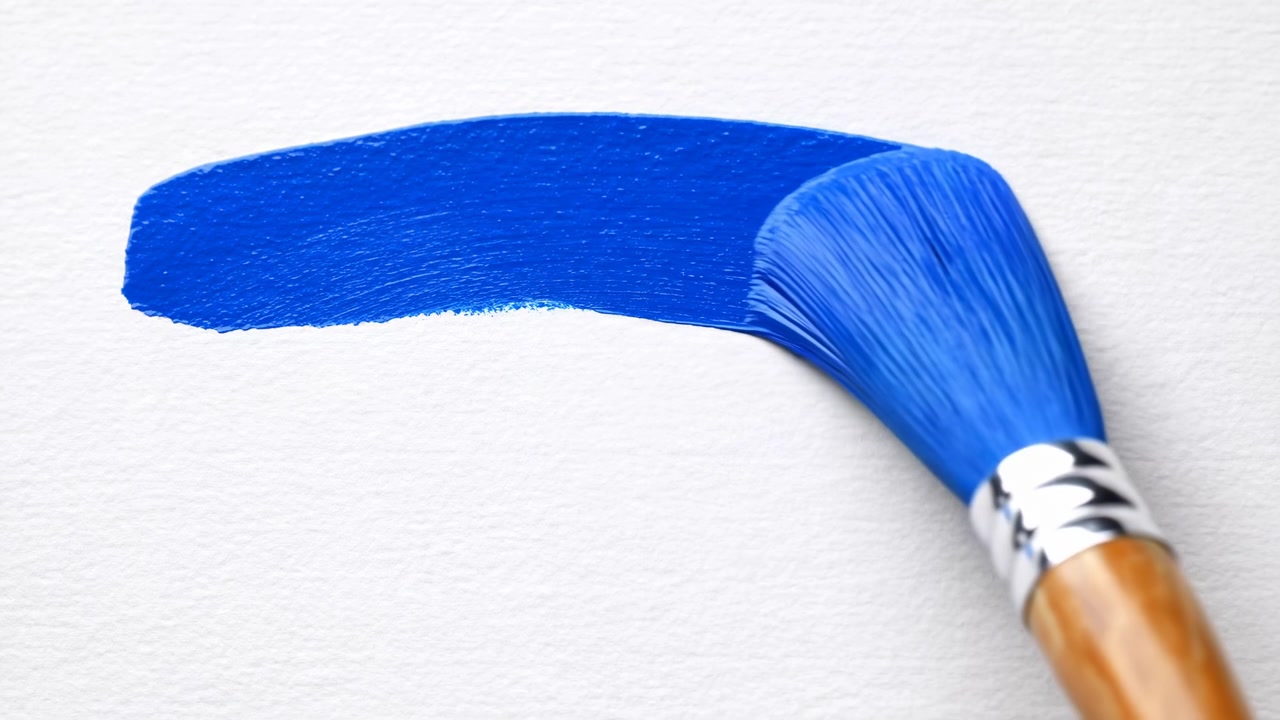 Pennellata di pittura blu su tela bianca, artista che testa un campione di cobalto con pennello a lingua di gatto, primo piano delle setole