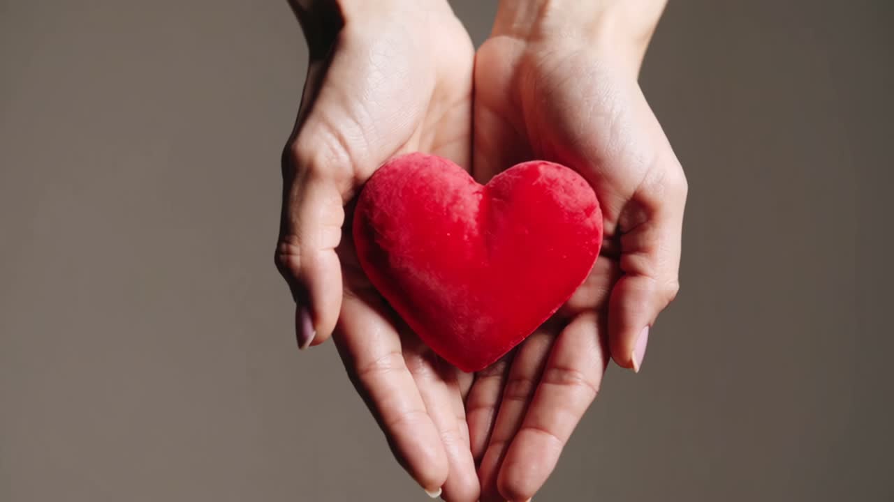 manos sosteniendo un corazón rojo