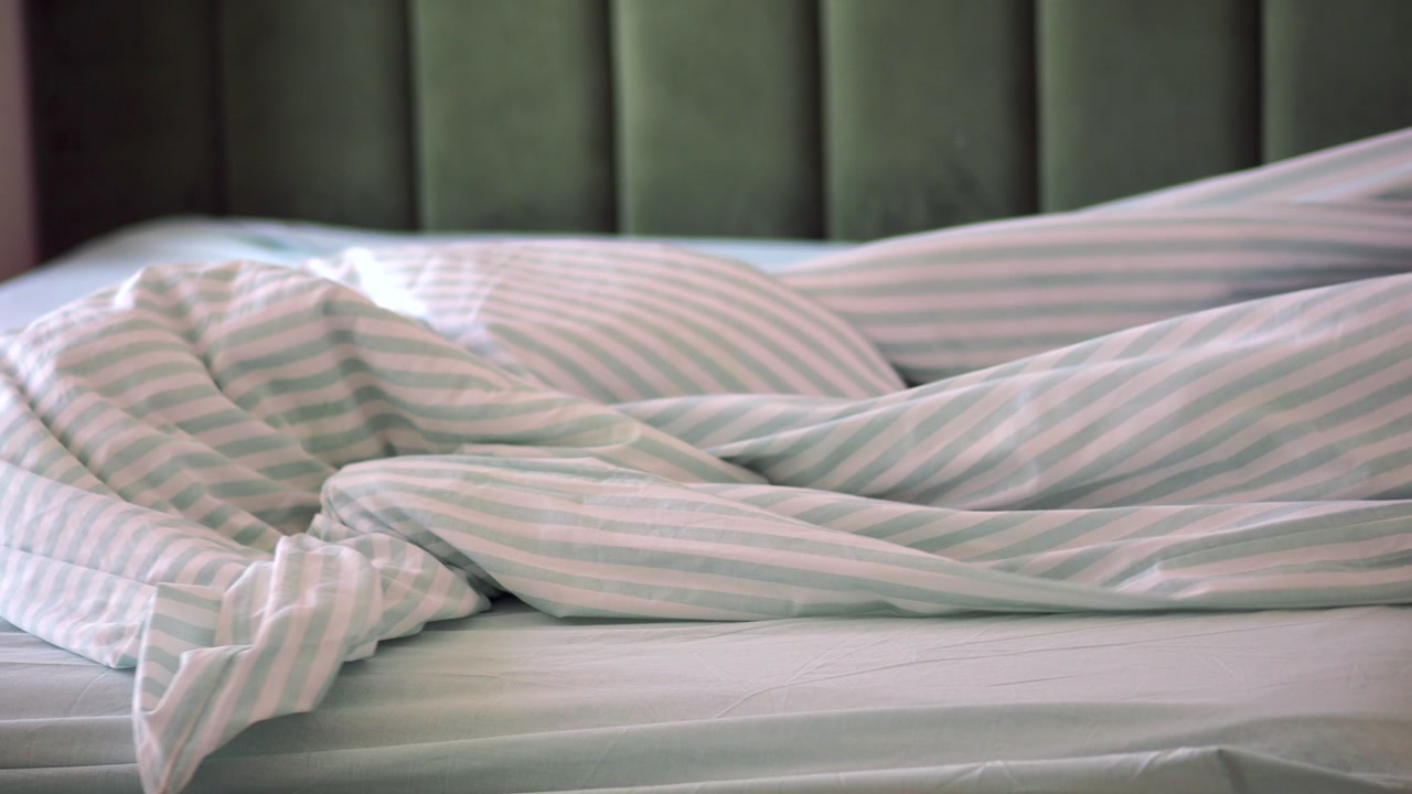 Person Making a Bed with Fresh Striped Duvet Cover