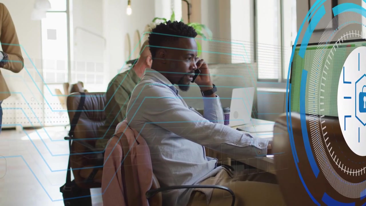 IT desk worker talking on call and typing, system generating security overlay flagging monitor data
