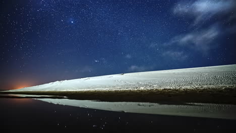 wonderful time lapse of the stars over sand dunes with the reflex of the stars projected on a lake