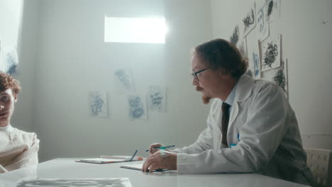 doctor attentively listening to patient in straitjacket in psychiatric ward