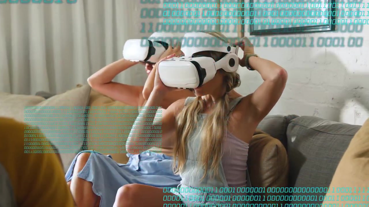 Mimo záběr podává sluchátka, dvě ženy si prohlížejí a nasazují VR jednotky na gauči, gestikulují uprostřed technologické ukázky.