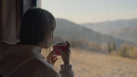 Woman enjoying a hot drink while looking at a mountain view