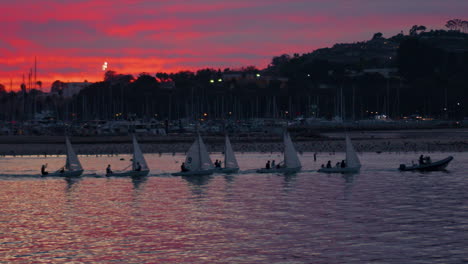 sailboats being towed through sea harbor to docks during beautiful colorful sunset on the ocean