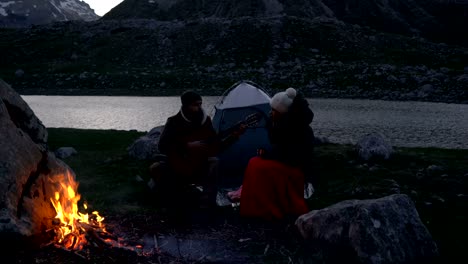 pareja de viajeros al anochecer cerca de un fuego de campamento