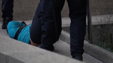 Police-Officer-Pulling-Protester-On-Ground-With-Its-Feet---Police-Violence-During-Protest-In-The-Hague,-Netherlands---cropped-shot,-focus-pull