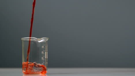 orange liquid pouring into beaker