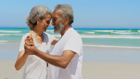 side view of romantic active senior african american couple dancing together on the beach 4k