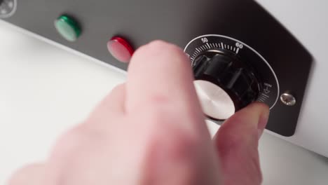 hand turns the power regulator on the panel of the electric device, increasing the load