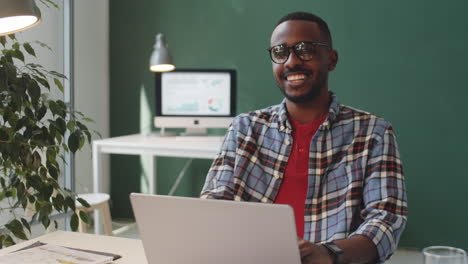 portrait of smiling african american man sitting at desk in office