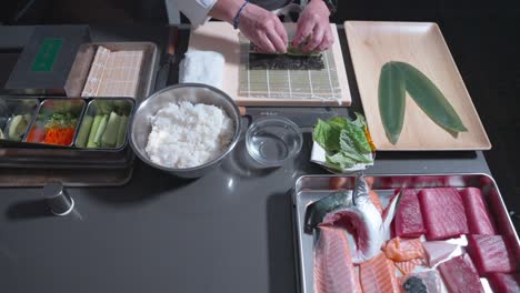 a static shot of a chef carefully placing fresh vegetables into a sushi roll, showcasing the attention to detail in the preparation process for a delicious and healthy sushi dish.