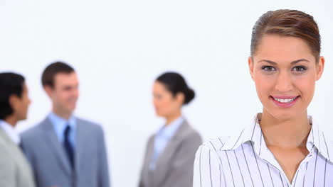 businesswoman looking at camera with colleagues in background