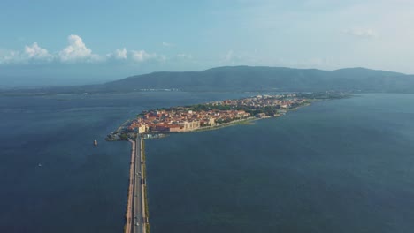 aerial drone flight above the old town orbetello island close to monte argentario and the maremma nature park in tuscany, italy, with blue sky and calm blue water