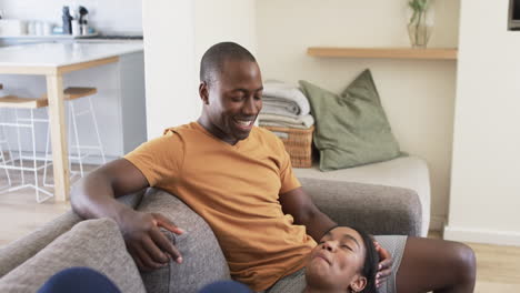 A-young-African-American-couple-relaxes-at-home,-warm-tones-throughout