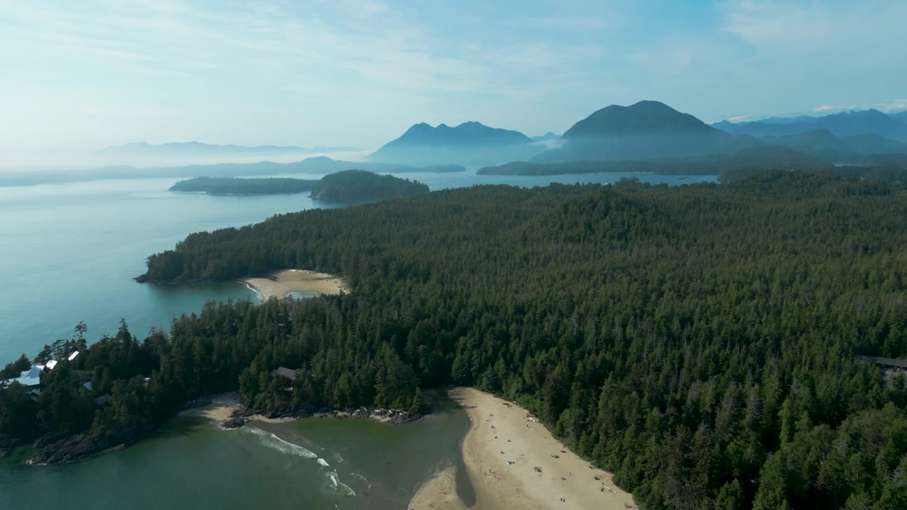 Ripresa aerea in allontanamento che rivela la spiaggia di Mackenzie a Tofino e la montagna dell'isola di Vancouver sullo sfondo in una giornata di sole nella Columbia Britannica, Canada